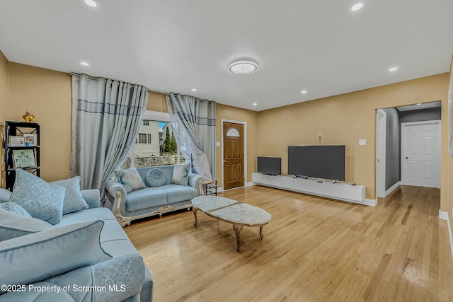 living area featuring baseboards, wood finished floors, and recessed lighting