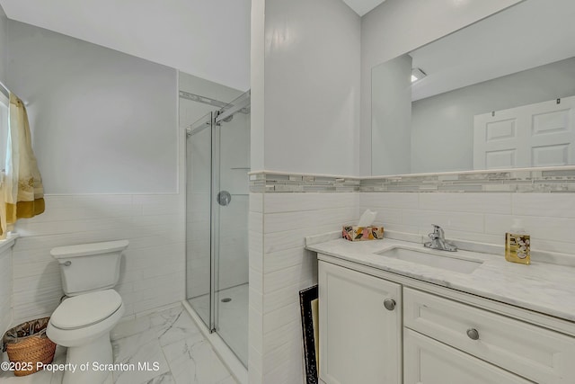 bathroom with tile walls, a wainscoted wall, marble finish floor, toilet, and a stall shower
