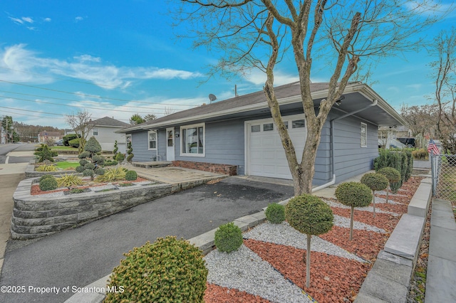 single story home with aphalt driveway, fence, and an attached garage