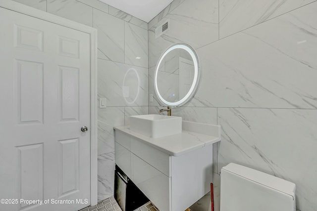 bathroom with tile walls, visible vents, toilet, and vanity