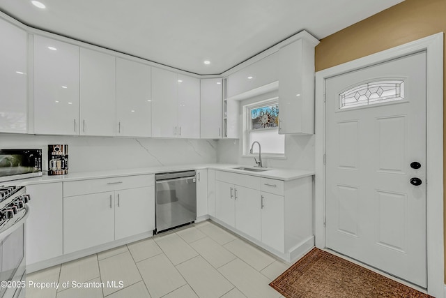 kitchen with white cabinets, light countertops, stainless steel appliances, tasteful backsplash, and a sink
