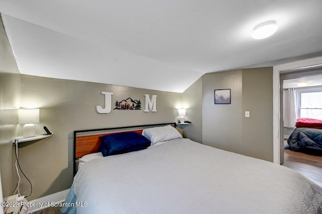 bedroom with hardwood / wood-style floors and lofted ceiling