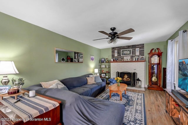 living room featuring light wood-type flooring, a brick fireplace, and ceiling fan