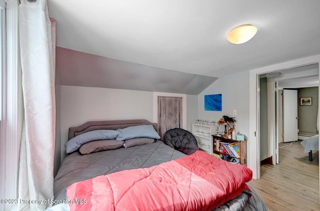 bedroom with light hardwood / wood-style floors, baseboard heating, and lofted ceiling