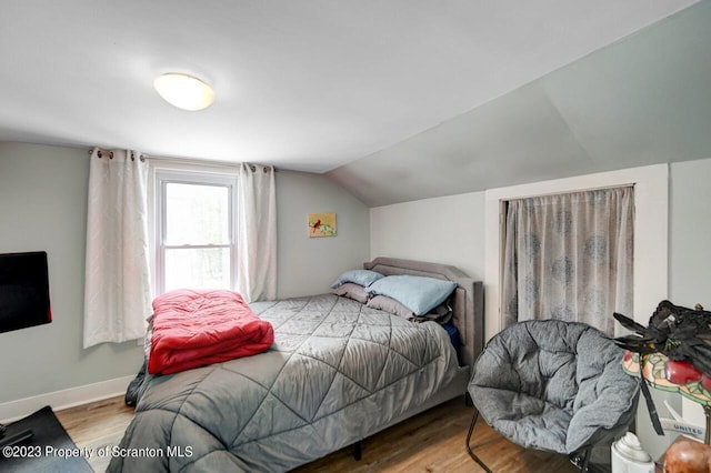 bedroom with hardwood / wood-style floors and lofted ceiling