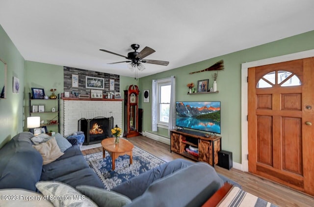 living room with ceiling fan, light wood-type flooring, and a fireplace