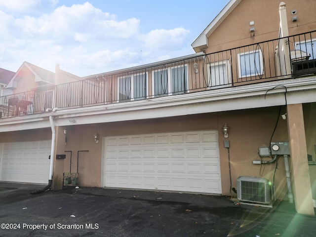 exterior space with central air condition unit, a balcony, and a garage