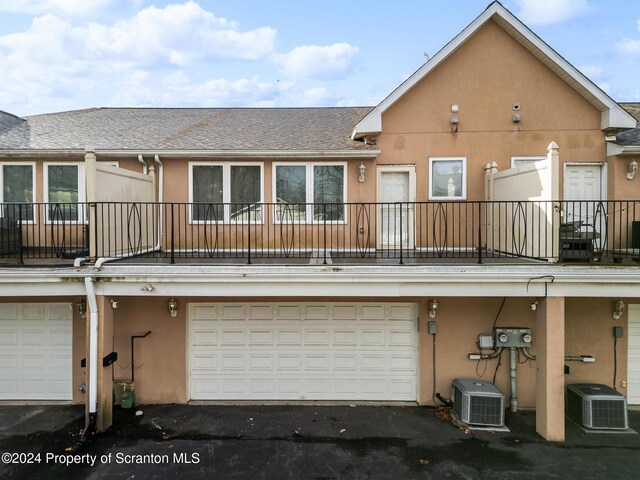 back of house with a garage, central air condition unit, and a balcony