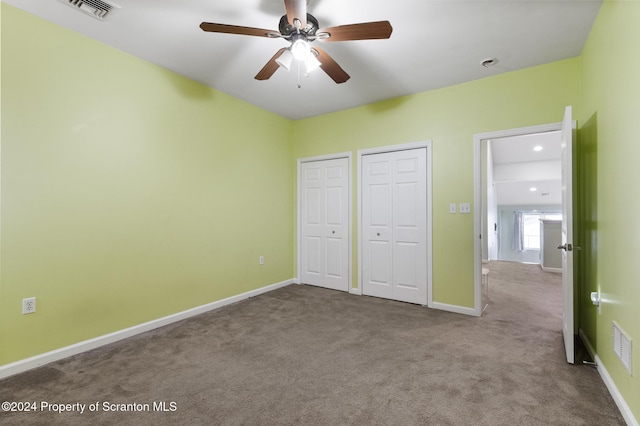 unfurnished bedroom with ceiling fan, carpet floors, and two closets