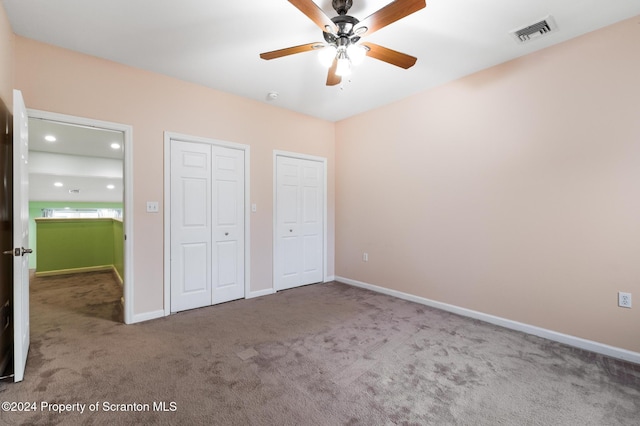 unfurnished bedroom with carpet flooring, multiple closets, and ceiling fan