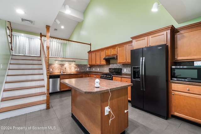 kitchen featuring decorative backsplash, sink, black appliances, high vaulted ceiling, and a kitchen island