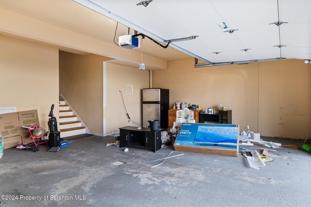 garage with a garage door opener and stainless steel refrigerator