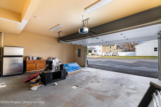 garage with electric panel, stainless steel fridge, and a garage door opener