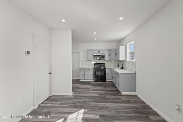 kitchen with sink, dark hardwood / wood-style flooring, gray cabinets, black gas range, and backsplash