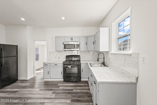 kitchen featuring sink, backsplash, dark wood-type flooring, and black appliances