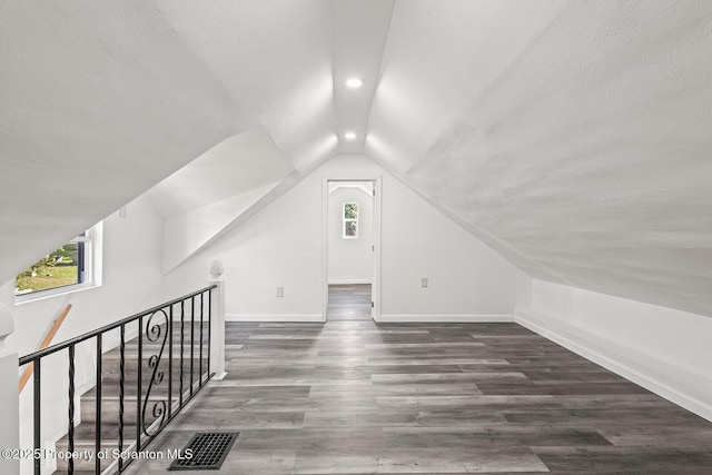 bonus room with dark hardwood / wood-style flooring, lofted ceiling, and a textured ceiling