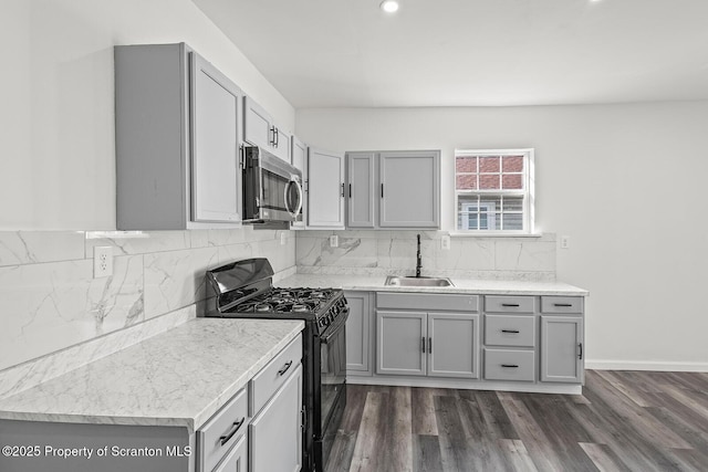 kitchen with gray cabinets, tasteful backsplash, sink, and black gas range