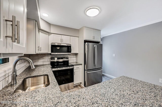 kitchen with tasteful backsplash, white cabinetry, sink, and appliances with stainless steel finishes