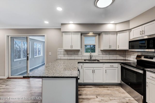 kitchen featuring backsplash, white cabinets, sink, dark stone countertops, and appliances with stainless steel finishes