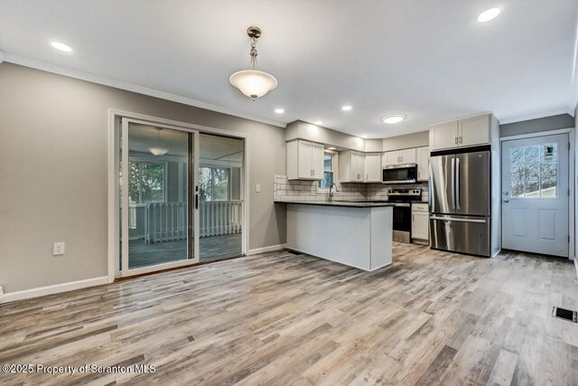 kitchen featuring white cabinets, hanging light fixtures, light hardwood / wood-style flooring, appliances with stainless steel finishes, and kitchen peninsula