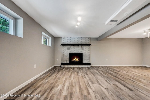 unfurnished living room with a fireplace, hardwood / wood-style flooring, and a healthy amount of sunlight