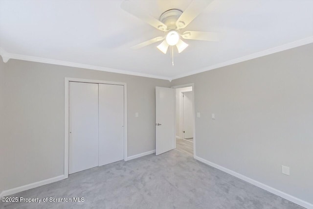 unfurnished bedroom with ceiling fan, a closet, crown molding, and light carpet