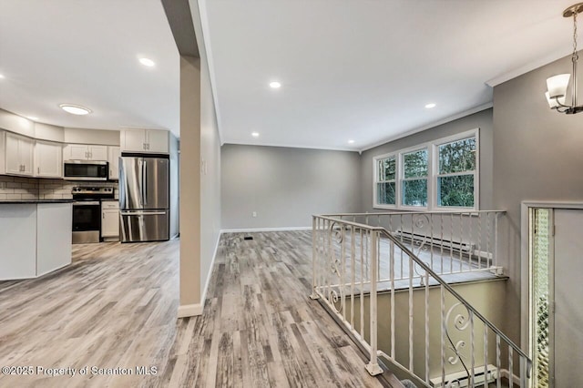 kitchen featuring white cabinetry, stainless steel appliances, decorative light fixtures, and light wood-type flooring