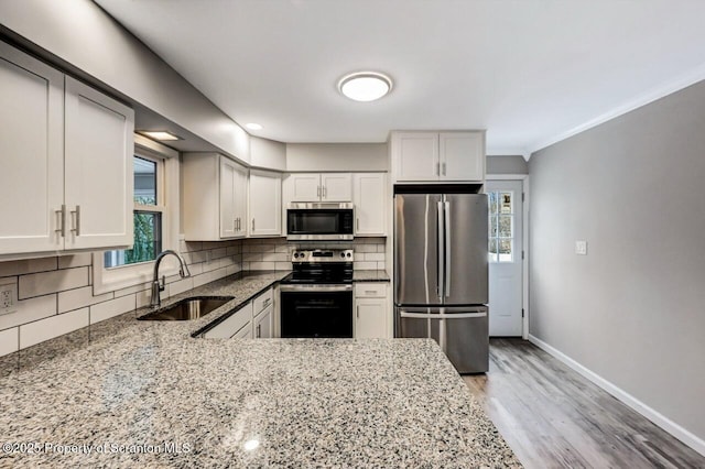 kitchen with decorative backsplash, light stone counters, white cabinets, and stainless steel appliances