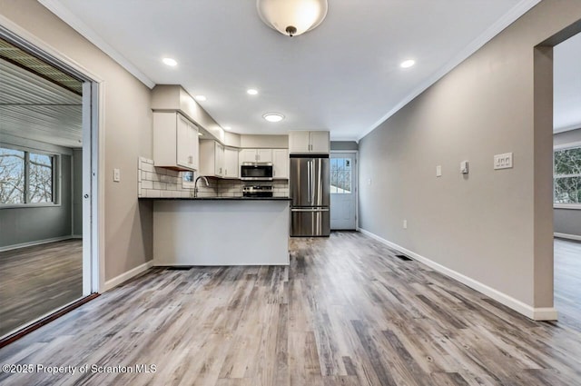 kitchen featuring sink, light wood-type flooring, white cabinetry, kitchen peninsula, and stainless steel appliances