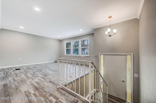 entryway featuring hardwood / wood-style floors, ornamental molding, and a notable chandelier