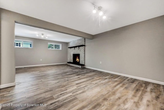 unfurnished living room featuring hardwood / wood-style flooring and a brick fireplace