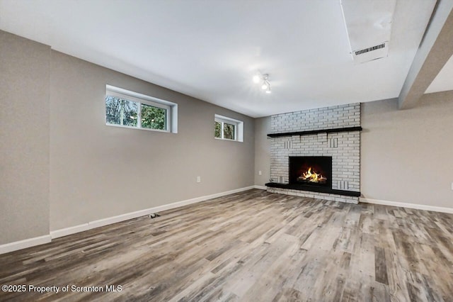 unfurnished living room with hardwood / wood-style floors and a brick fireplace