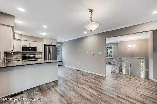 kitchen with backsplash, stainless steel appliances, sink, decorative light fixtures, and white cabinets