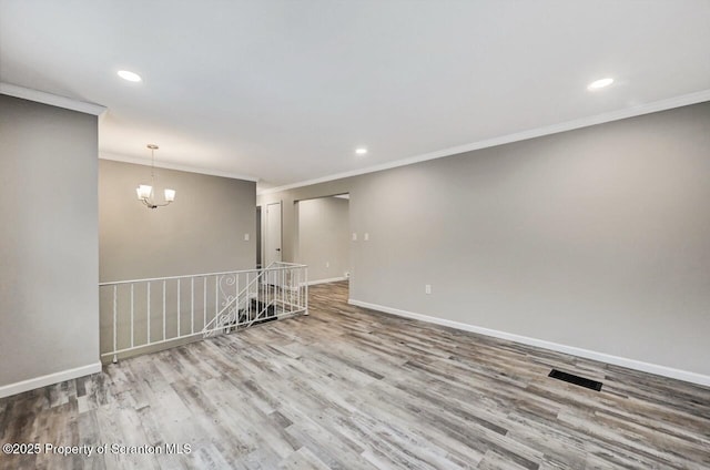 unfurnished room featuring light hardwood / wood-style floors, crown molding, and a notable chandelier