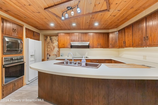 kitchen with kitchen peninsula, built in microwave, light hardwood / wood-style flooring, black oven, and white fridge with ice dispenser