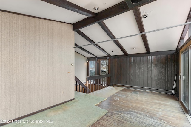 spare room featuring lofted ceiling with beams and light wood-type flooring