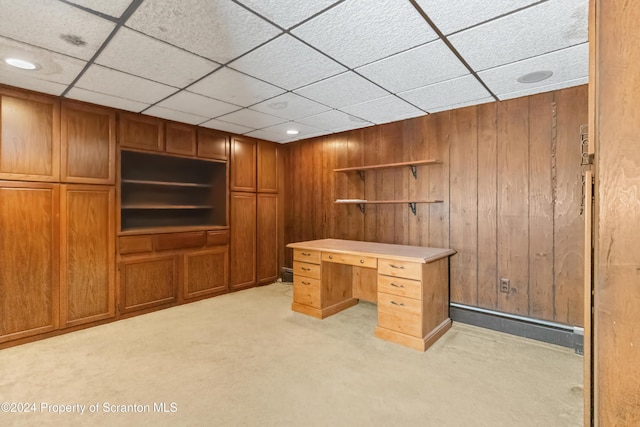 unfurnished office with light colored carpet, baseboard heating, and wooden walls