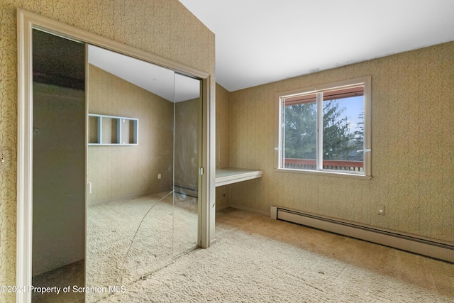 unfurnished bedroom featuring baseboard heating, carpet flooring, a closet, and lofted ceiling