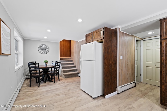 kitchen with white refrigerator, a baseboard radiator, crown molding, and wood walls