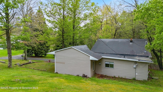 back of house with a shingled roof and a lawn