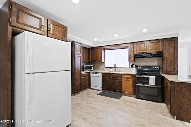 kitchen with sink, white appliances, light hardwood / wood-style flooring, backsplash, and light stone counters