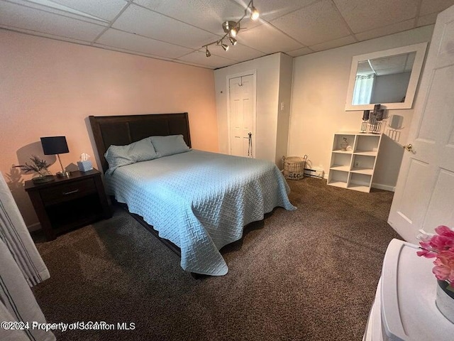 carpeted bedroom with a paneled ceiling and a baseboard radiator