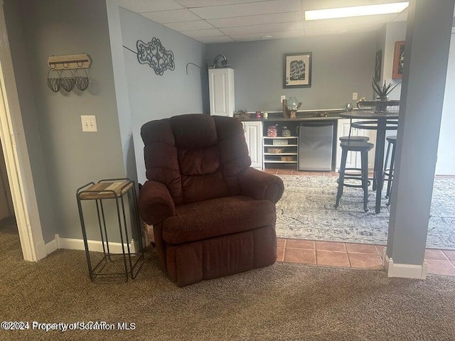 living area with carpet flooring and a paneled ceiling