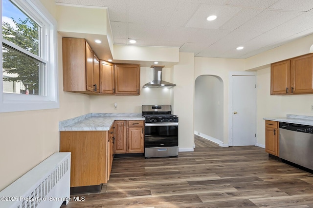 1324 Dartmouth St, Scranton, PA 18504 - kitchen with appliances with stainless steel finishes, wall chimney range hood, radiator, arched walkways, and light countertops