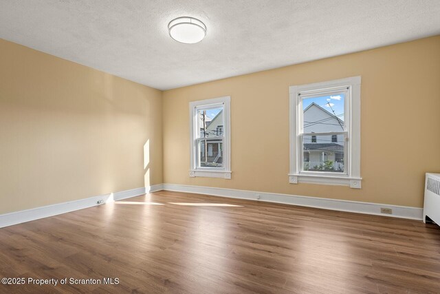 1324 Dartmouth St, Scranton, PA 18504 - spare room featuring plenty of natural light, wood finished floors, a textured ceiling, and radiator