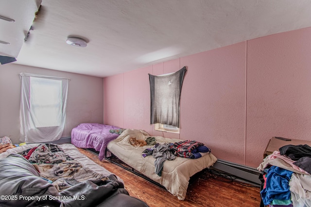bedroom with wood-type flooring and baseboard heating