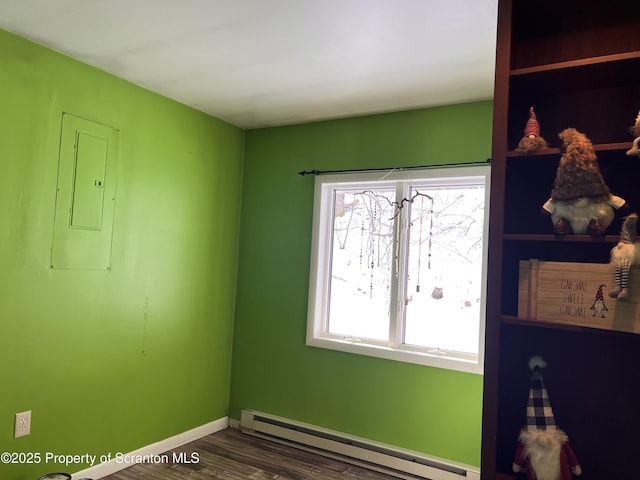 empty room featuring wood-type flooring, a wealth of natural light, electric panel, and a baseboard heating unit