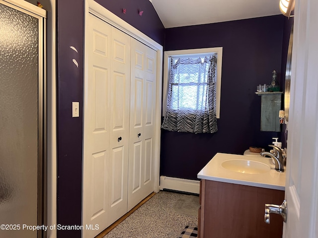 bathroom with walk in shower, vanity, and a baseboard heating unit