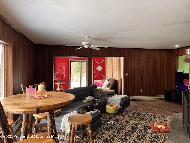 living room featuring a baseboard radiator, dark hardwood / wood-style floors, ceiling fan, and wood walls