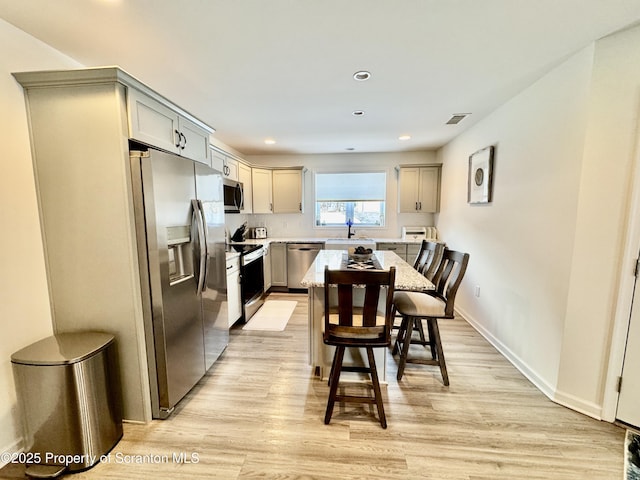 kitchen with sink, gray cabinetry, a center island, stainless steel appliances, and light hardwood / wood-style floors